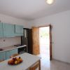 Cucina semplice con tavolo e porta verso un cortile.