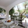 Veranda bianca con tavolo, sedie e alberi intorno.