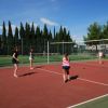 Persone giocano a pallavolo su un campo all'aperto.