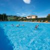 Persone nuotano in una grande piscina azzurra.