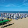 Spiaggia con lettini blu e ombrelloni.
