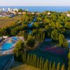 Vista aerea di piscine e campi sportivi tra alberi.