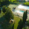 Piscina e campi sportivi circondati da alberi, vista dall'alto.