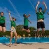 Persone che saltano in aria davanti a una piscina.