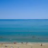 Spiaggia con persone in acqua e cielo limpido.