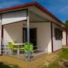 Bungalow bianco con patio e sedie verdi.
