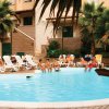Piscina all'aperto circondata da lettini, persone rilassate e palme.