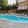 Piscina a forma irregolare circondata da lettini e immersa nel verde.