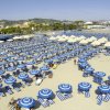 Una spiaggia con ombrelloni blu e bianchi allineati sulla sabbia.
