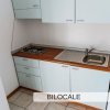 Una piccola cucina con lavello, fornelli e armadietti chiari.