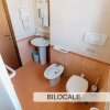Bagno con lavabo, bidet e WC. Interni in piastrelle beige.