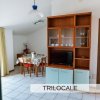 Interno di un trilocale con tavolo da pranzo, mobile e TV su pavimento piastrellato.