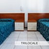 Due letti singoli con copriletti blu, separati da un comodino in legno.