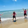 Tre persone sorridenti vestite di rosa sulla spiaggia.