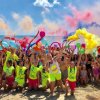 Grande gruppo sulla spiaggia con palloncini e fumogeni colorati.