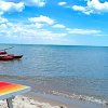 Una spiaggia con una barca rossa sull'acqua e un lettino giallo e arancione sulla sabbia.