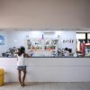 Interno di un bar con una persona che ordina al bancone bianco.