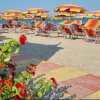 Spiaggia con ombrelloni colorati e fiori rossi in primo piano.