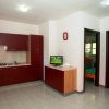 Cucina moderna con mobili rossi, piccola TV e due porte aperte.