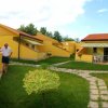 Un complesso di bungalow gialli con vialetti in pietra e persone conversano all'esterno.