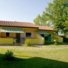 Due bungalow gialli con tende da sole verdi in un giardino verde con alberi.