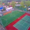 Un campo da calcio e un campo da tennis, circondati da alberi e strutture.