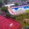 Un campo da basket rosso e una grande piscina con lettini e ombrelloni gialli.