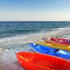 Canoe rosse, blu e gialle sulla spiaggia vicino al mare.