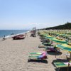 Ombrelloni verdi e gialli su una spiaggia sabbiosa affiancata dal mare.