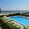 Una piscina circondata da ombrelloni gialli e verdi, con vista sul mare.