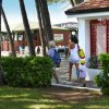 Persone che camminano tra alberi e cespugli verso un edificio.