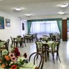 Sala da pranzo con tavoli e sedie in legno, tovaglie a quadri.