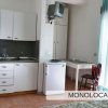 Vista su una cucina con tavolo, sedie e mini-frigo in un monolocale.