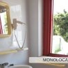 Bagno con specchio, lavabo e asciugacapelli vicino a una finestra.