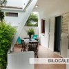 Veranda esterna di un bilocale con tavolo, sedie e piante.