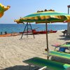 Spiaggia sabbiosa con ombrelloni colorati, lettini e una torre di salvataggio vicino al mare.