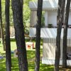 Balconi di un edificio bianco visti tra alti alberi, con case da gioco per bambini su prato.