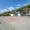 Un campo da tennis all'aperto con recinzione, cielo blu e alberi sullo sfondo.