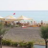 Spiaggia con ombrelloni gialli, capannone e mare sullo sfondo.