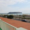 Balcone con vista sulla spiaggia, strada e promontorio in lontananza.