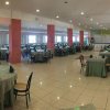Ampia sala da pranzo con tavoli rotondi apparecchiati, colonne rosa e pavimento piastrellato.