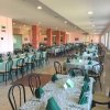 Vista di una sala da pranzo con tavoli apparecchiati, sedie nere e tovaglioli verdi.