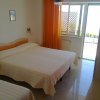 Camera con letto matrimoniale, tende arancioni e porta finestra aperta su un balcone.