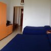 Camera con letto matrimoniale, TV su scrivania, armadio arancione e singolo letto con coperta blu.