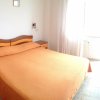 Camera con letto matrimoniale e copriletto arancione, accanto al balcone con luce naturale.