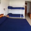 Grande camera con letto matrimoniale blu, letti a castello, armadio arancione e fiori.
