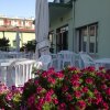 Terrazza con sedie bianche e ombrelloni, circondata da fiori viola.
