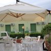 Tavoli e sedie bianche sotto un grande ombrellone su una terrazza.
