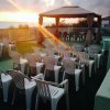 Sedie bianche rivolte verso un gazebo al tramonto su una terrazza vista mare.