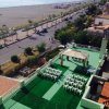 Vista dall'alto di una terrazza con sedie bianche e gazebo, vicino a una spiaggia.